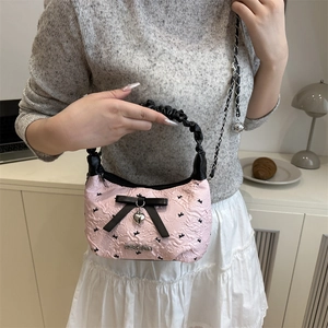 Pink pleated handbag with black ribbon bow and rabbit pattern shown on model