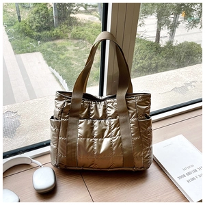 Detailaufnahme der goldenen Stepp-Tragetasche mit Metallic-Textur und Seitentasche
