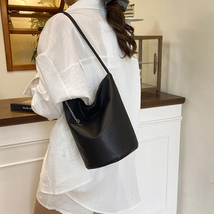 Sac seau minimaliste en cuir noir avec détail de chaîne pour les trajets quotidiens