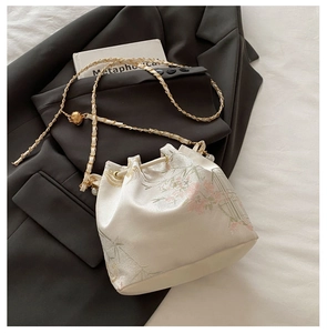 Detail of floral bucket bag with pearl chain strap and gold hardware on black blazer
