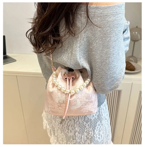 Close-up of pink satin bucket bag with exquisite embroidery and pearl chain handle