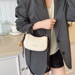 Sac demi-lune chic en cuir crème avec bandoulière marron et breloque baseball