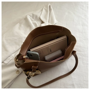 Detail view of large brown leather tote bag interior with floral scarf and daily essentials