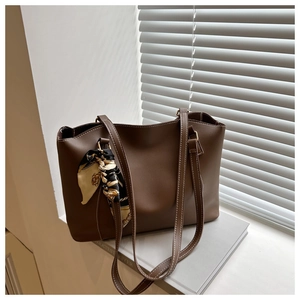Detail of vintage brown leather tote bag with white stitching and printed silk scarf
