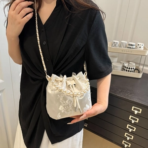 Elegant white embroidered bucket bag with pearl handle and golden chain strap