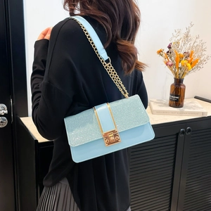 Sac bandoulière bleu clair à paillettes avec chaîne dorée porté par un mannequin chic
