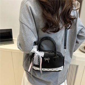 Chic black leather Boston bag with white lace heart trim and side ribbon bow