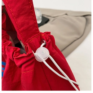 Detail of red fabric tote bag with white drawstring cord and transparent plastic toggle