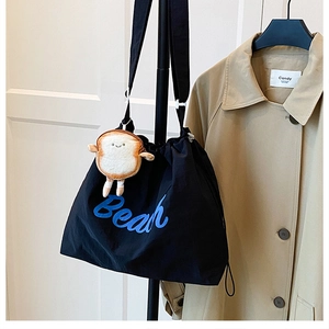 Detail of black drawstring tote bag with blue Bear print and cute smiley bread charm