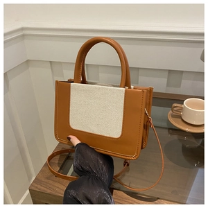 Detail shot of caramel leather and white canvas patchwork on casual crossbody bag