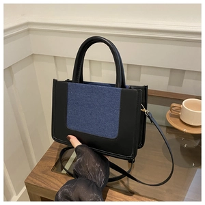 Detail of the blue denim and black leather stitching on a compact crossbody bag