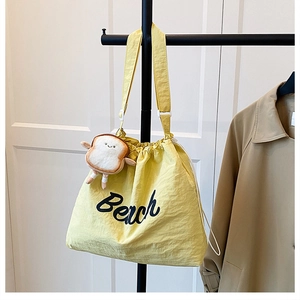 Detail of yellow drawstring tote bag with Beach print and cute toast plush charm