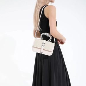 Minimalist beige crossbody bag with artistic silver fluid handle and woven flap detail