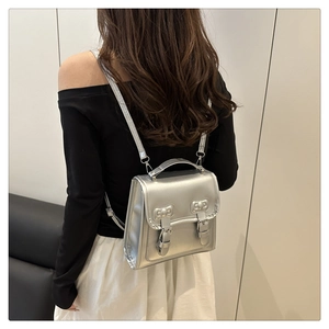 Détail d'un mini sac à dos argenté métallisé avec nœuds et fermeture à boucle en métal