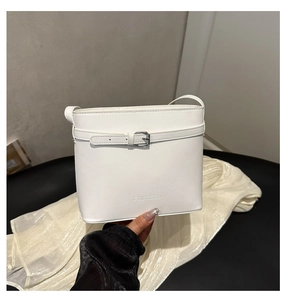 Detail of white leather bucket bag with silver metal buckle and embossed logo