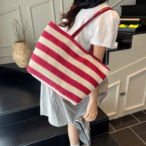 Red and white striped woven tote bag with slim red leather straps on a model