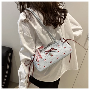 Détail du sac sous l'aisselle bleu clair avec nœuds rouges et pendentif coeur en métal