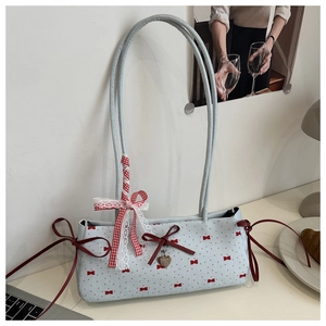 Détail du sac bandoulière bleu clair avec nœuds rouges, rubans en dentelle et pendentif