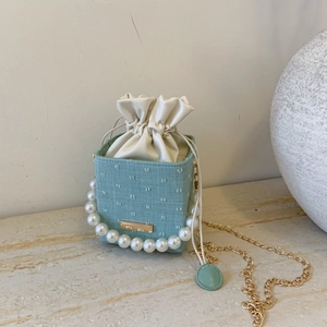 Detail of mint green polka dot mini box bag with pearl handle and golden chain strap