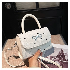 Détail du sac en cuir plissé blanc avec imprimé nœuds et fermoir papillon argenté