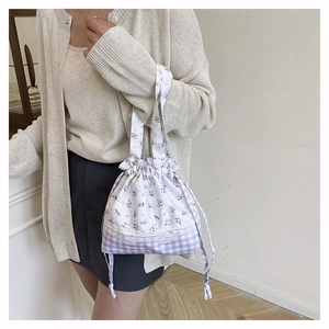 Detail of sweet floral lace bucket bag with drawstring closure and plaid fabric textures