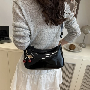 Minimalist black patent leather underarm shoulder bag with a decorative red cherry charm