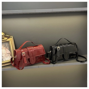 Close-up of glossy patent leather handbags in burgundy and black with gold hardware details