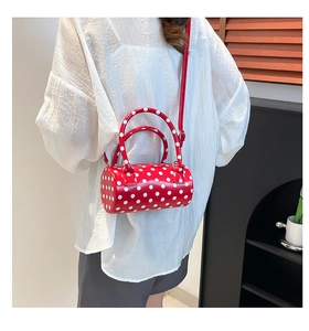 Rear view of a model wearing the red polka dot barrel bag with a stylish long strap