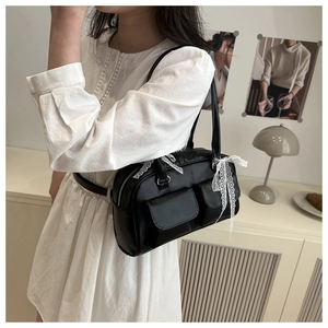 Détail du sac à épaule en similicuir noir avec nœuds en dentelle et poches à rabat
