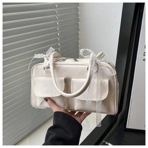 Détail du sac à main en similicuir crème avec nœuds en dentelle et doubles poches avant