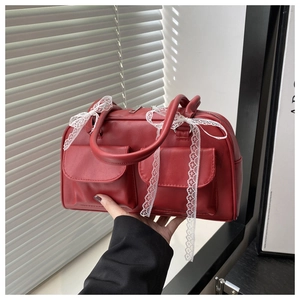 Détail du sac polochon vintage rouge foncé avec nœud en dentelle blanche et similicuir