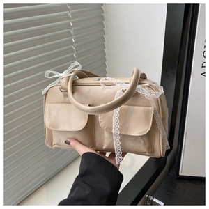 Détail du sac Boston beige avec nœud en dentelle et poches frontales en décor de style