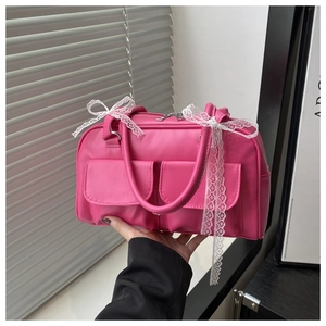 Détails d'un sac à main rose vif en similicuir avec des nœuds en dentelle et deux poches