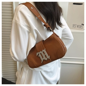 Detail view of a vintage brown leather baguette bag with a silver metal M-shaped buckle