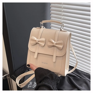 Detail shot of a beige PU leather backpack featuring cute bow accents and silver lettering