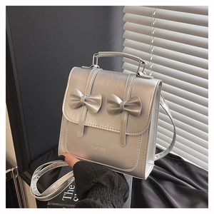 Detail of silver metallic PU handbag with bow accents and FASHION embossed logo