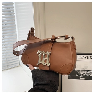 Detailed view of caramel brown baguette bag with silver M buckle and adjustable strap
