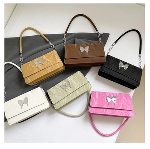 Detail of six butterfly pleat shoulder bags in multiple colors with metallic chains