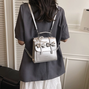 Silver bow-knot backpack in metallic PU with pearl pendant and top handle strap