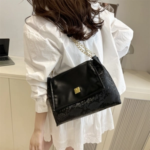 Fashionable black faux snake-skin shoulder bag with gold chain strap and metal lock