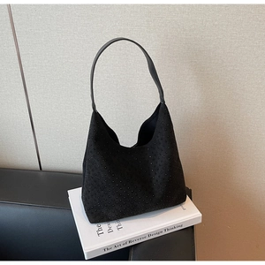 Detail of black suede hobo bag with sparkling rhinestones on a white book