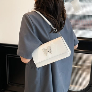 White underarm bag with silver butterfly buckle and leather strap on model