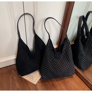 Detail view of black suede hobo bags with silver and black rivets on wooden floor