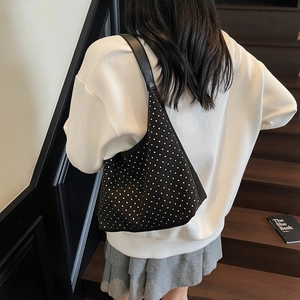 Chic black canvas tote bag with polka dot studs shown on a model in a modern staircase setting