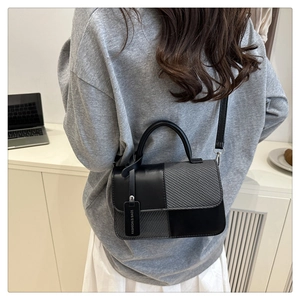 Lifestyle shot of woman carrying a retro color-block handbag with woven texture and top handle