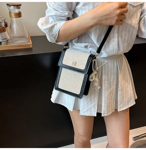 Detail showing canvas and leather mini crossbody bag with a floral gold buckle and plush charm