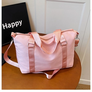 Detail of pink travel duffel bag with reinforced handles and silver metal hardware