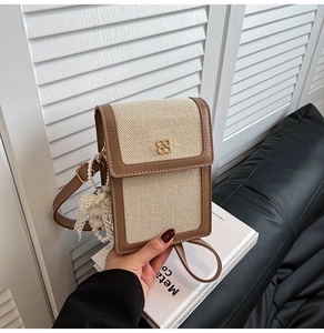 Detail of canvas and leather crossbody bag with clover logo and plush pendant