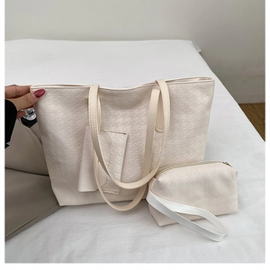 Detail view of cream white woven texture tote bag and matching smaller zip pouch set