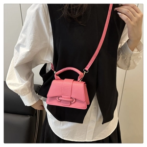 Detail of pink leathery mini crossbody bag featuring a curved base and metal ring closure